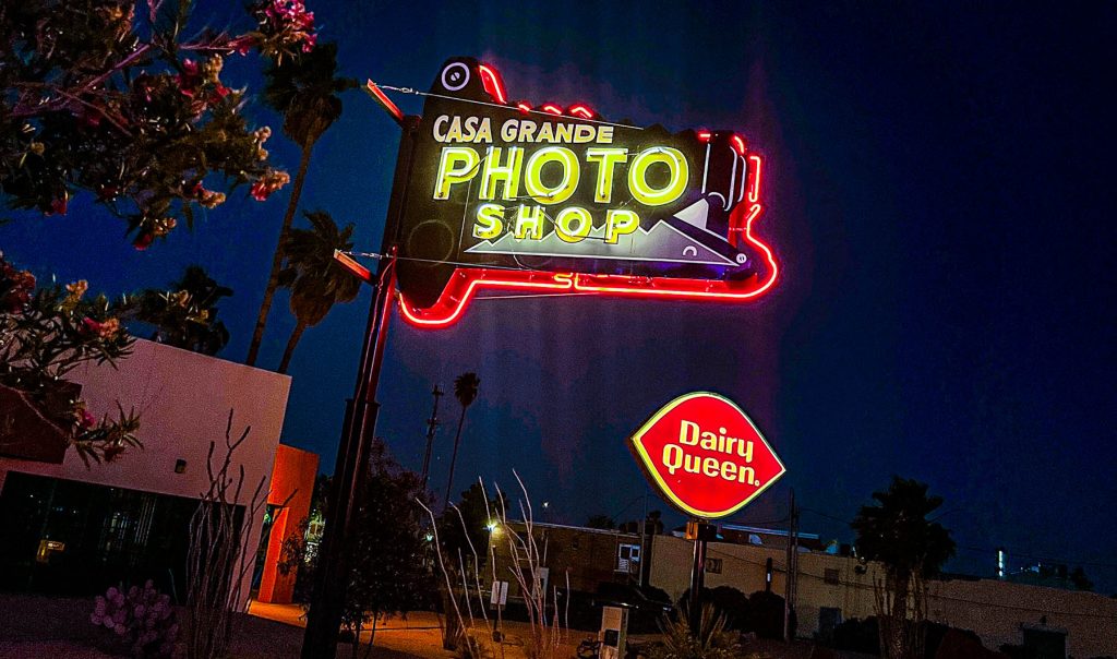 nighttime photo of a neon sign for the casa grande photo shop and dairy queen